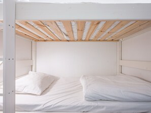 Un letto a castello con biancheria bianca e listelli di legno al soffitto.