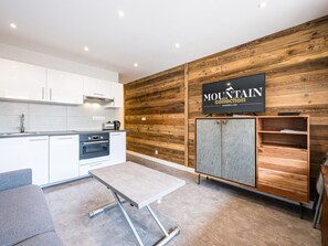 Una cucina moderna con mobili bianchi, forno integrato e parete in legno con insegna 'MOUNTAIN collection'.