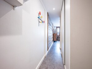 A hallway with a wooden wall, a white ceiling, and a grey floor.