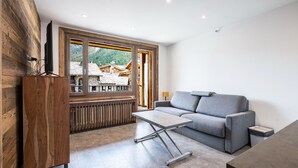 A modern living room with a sofa, coffee table, and wooden accents. - Renovated studio cabin ski-in/ski-out, Val-d'Isère (Val-d'Isère)