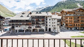A multi-story hotel with stone and wooden facades, balconies, and a view of snow-capped mountains. - Renovated studio cabin ski-in/ski-out, Val-d'Isère (Val-d'Isère)
