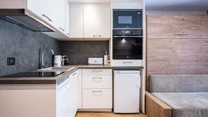 Una cuina compacta amb armaris blancs, forn integrat i rentaplats.