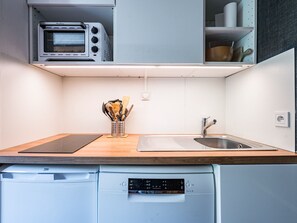 Uma cozinha compacta com torradeira embutida, pia e máquina de lavar louça.