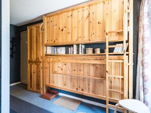 A room with a wooden bookshelf, a ladder, and a small table.