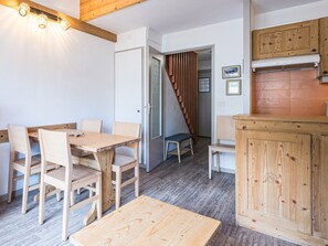Une pièce comprenant une table et des chaises en bois, un petit meuble en bois et un escalier menant à une autre pièce.