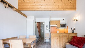 A modern kitchen with wooden cabinets, a microwave, and a red throw pillow on the sofa.