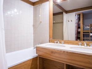 A bathroom with two sinks, a bathtub, and a shower.