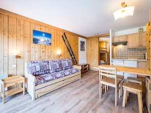 A wooden interior with a sofa, wooden tables, and a bunk bed.
