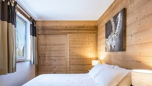 A wooden-paneled room with a bed, a nightstand, and a painting on the wall.