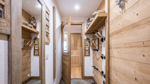 A narrow hallway with wooden walls, a bench, and a door leading to another room.