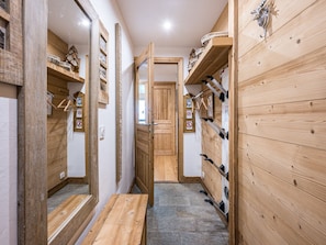Un couloir étroit aux murs en bois, avec un banc et une porte donnant sur une autre piÚce.