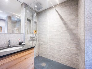 Une salle de bain moderne avec une douche à parois de verre, un meuble-lavabo en bois et un grand miroir.