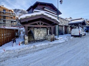Un bâtiment en pierre avec un étage supérieur en bois et une entrée abritée.