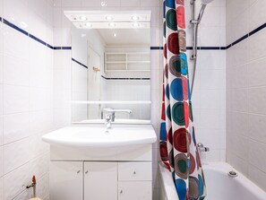 A bathroom with a white sink, mirror, and shower curtain with a circular pattern.
