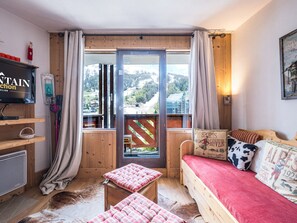 A cozy room with a wooden bed, a television, and a window with a view of a mountainous landscape.