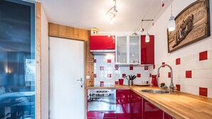 A modern kitchen with red cabinets, a stainless steel dishwasher, and a wooden countertop. - Cozy 2-room apartment in La Daille, 4 people, ski-in/ski-out (Val-d'Isère)