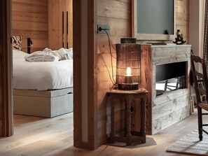 A bedroom with a bed, a bedside table with a candle, and a wooden wall.