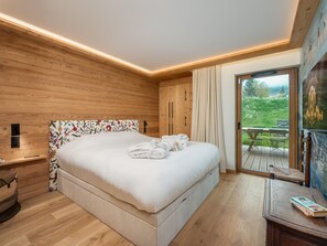 A bedroom with a wooden headboard, a large bed, a bedside table with a lamp, and a view of an outdoor deck.