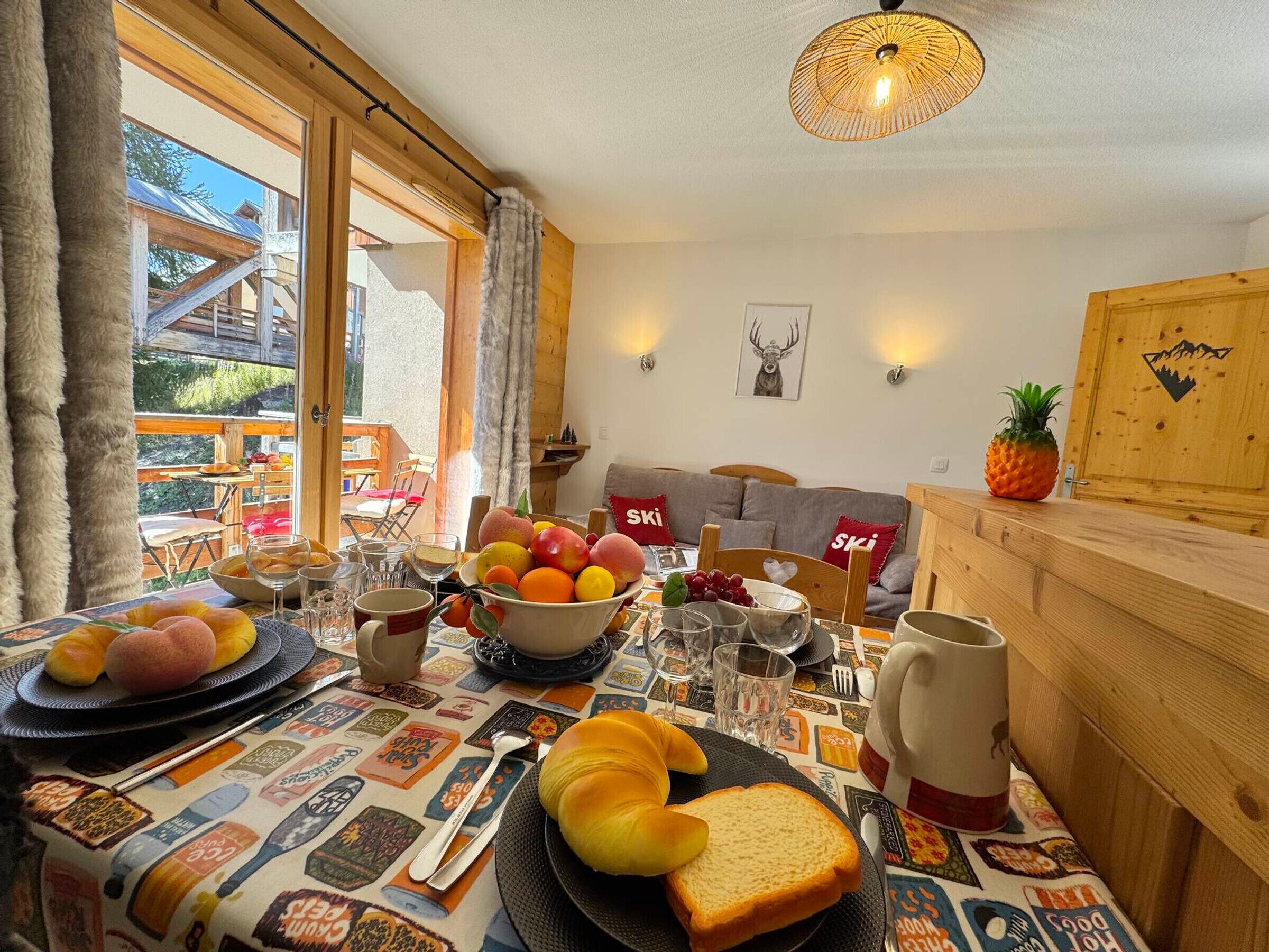 A dining area with a table set for breakfast, including bread, fruit, and a coffee mug.