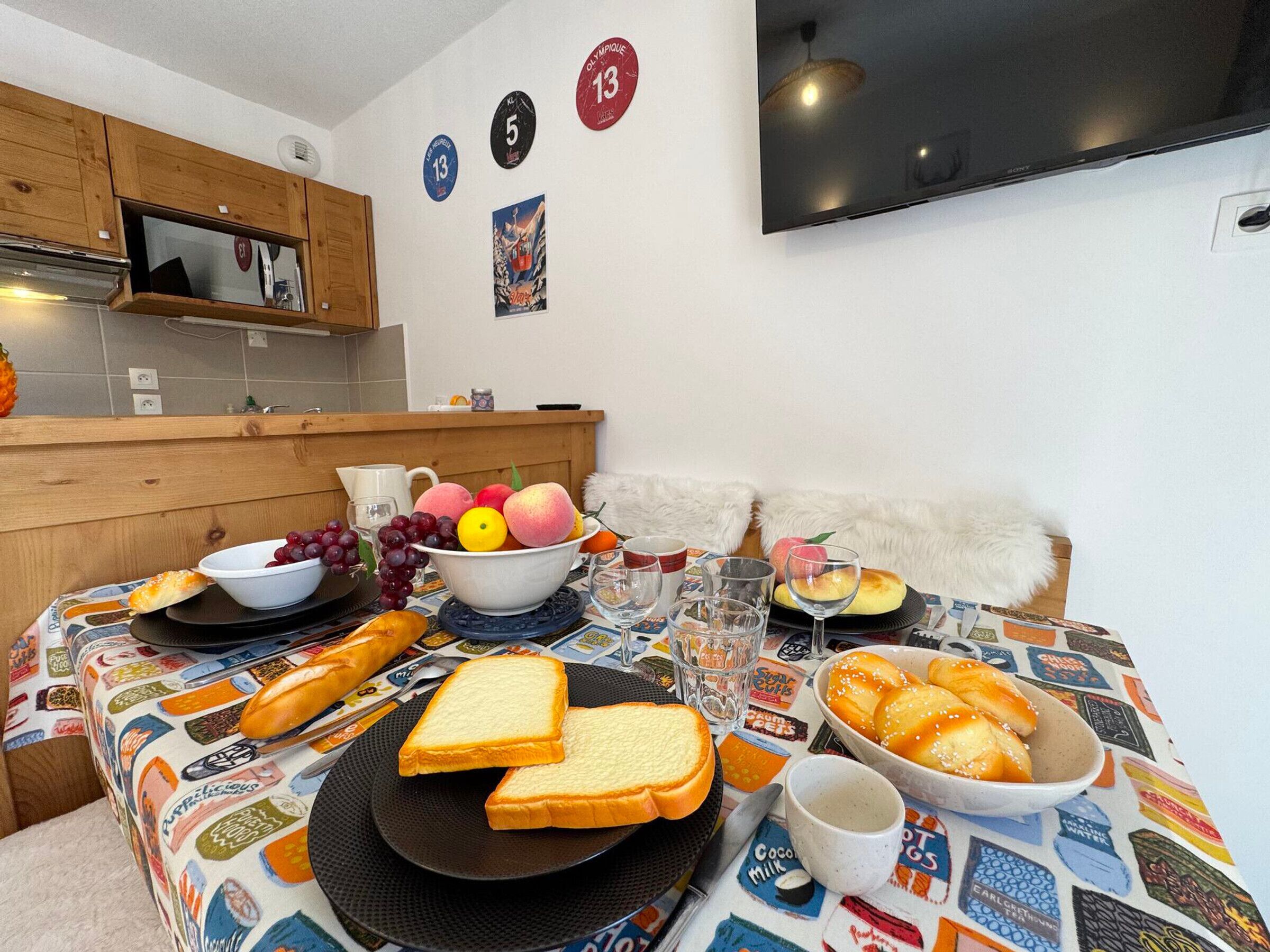 Una mesa de comedor con diversos alimentos, como pan, frutas y un tazón de uvas.