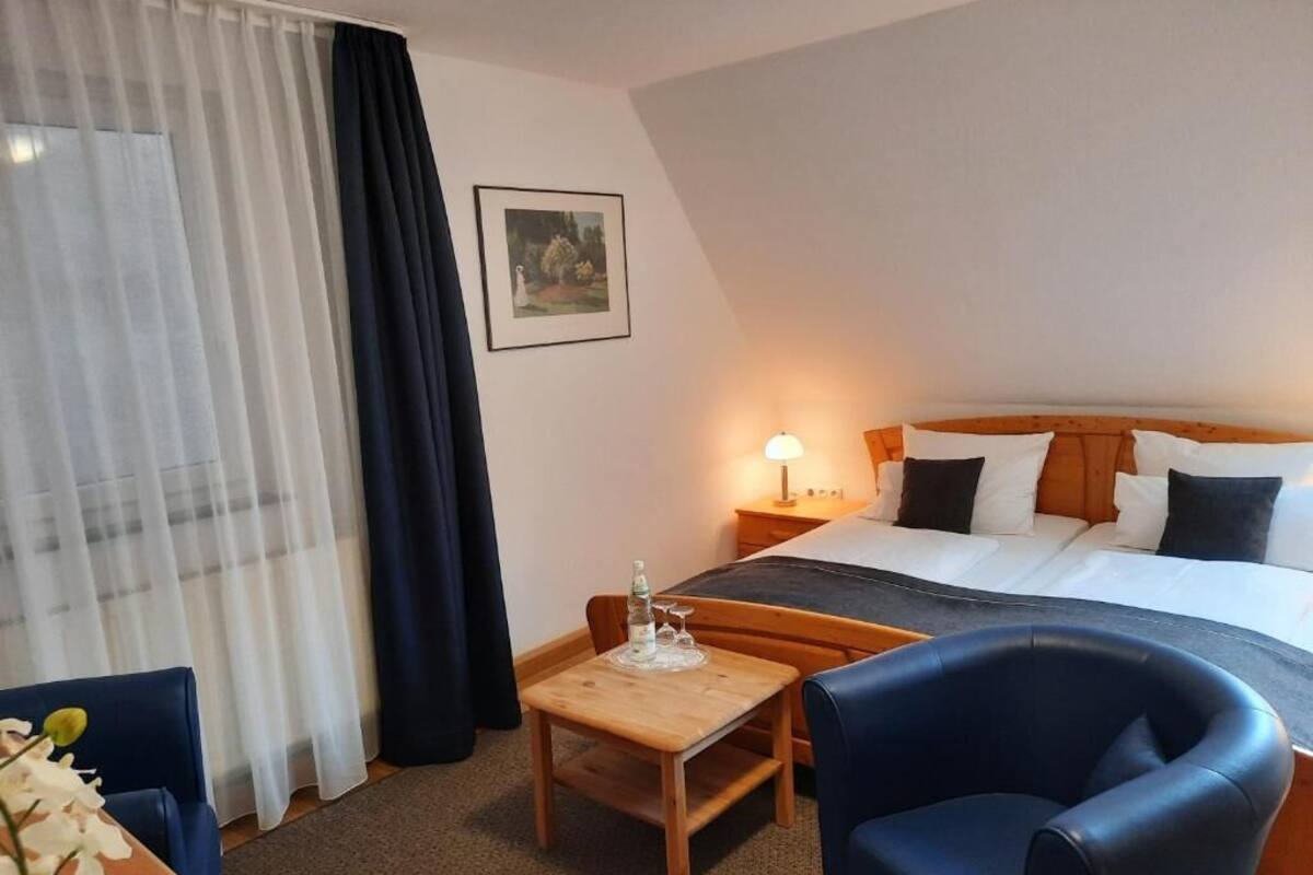 Een hotelkamer met een bed, een bureau, een stoel, een lamp en een schilderij aan de muur.