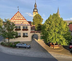 A traditional building with a red-tiled roof, a clock tower, and a stone archway. - Landgasthof May (Willanzheim)