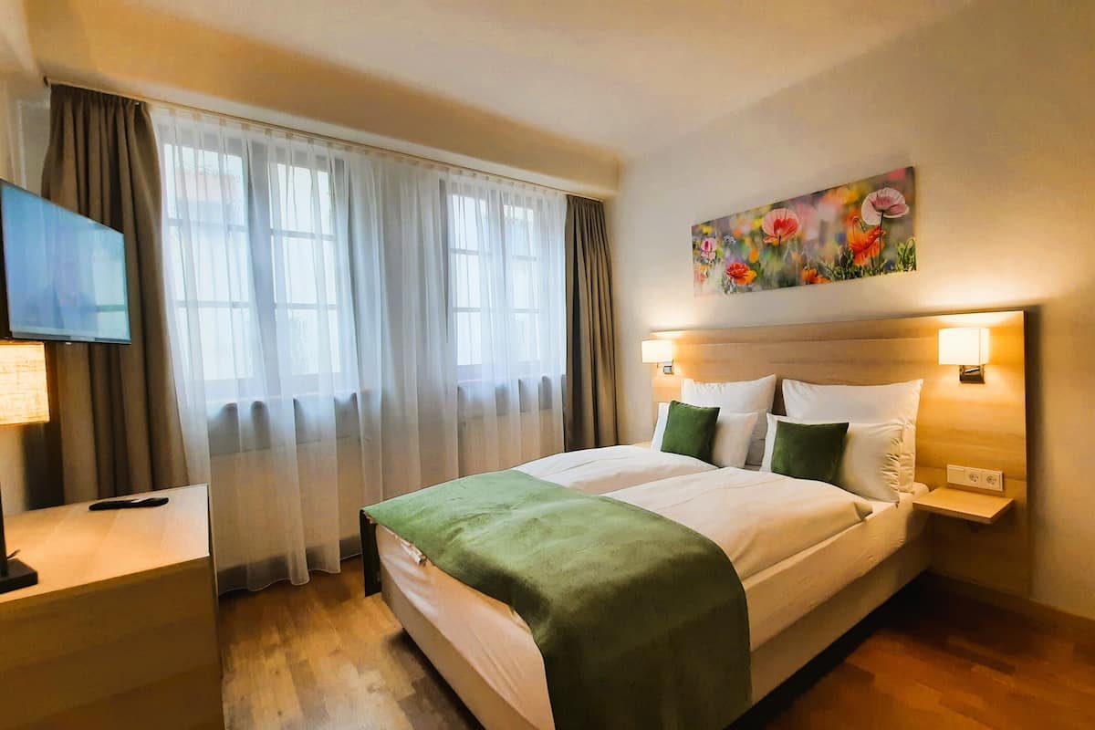 Een hotelkamer met een bed, een televisie, een schilderij en een lamp.