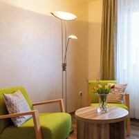 Una sala de estar moderna con un sofá verde, una mesa de centro redonda de madera y una lámpara de pie.