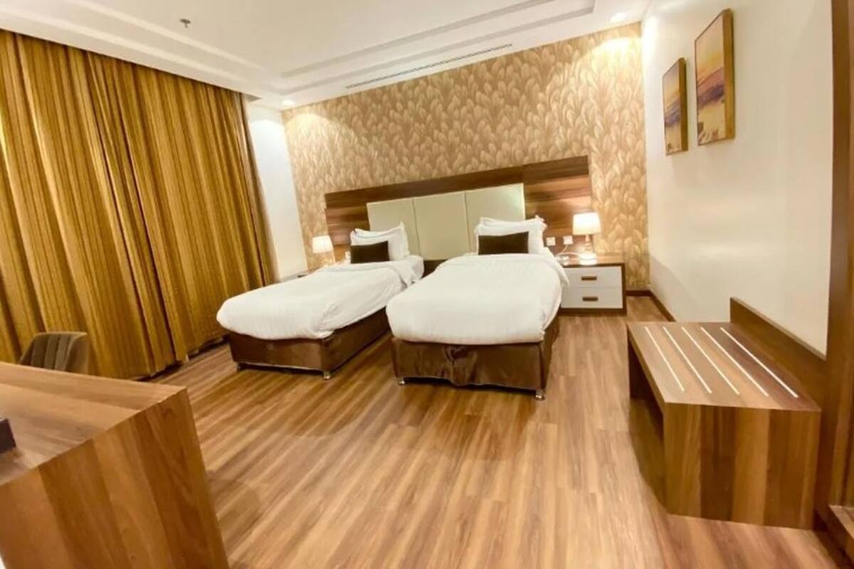 Une chambre d’hôtel avec deux lits, un plancher en bois, un grand miroir au-dessus des lits et un bureau en bois.