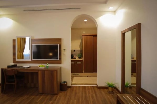 Een moderne hotelkamer met een houten bureau, een flatscreen televisie en een grote spiegel.