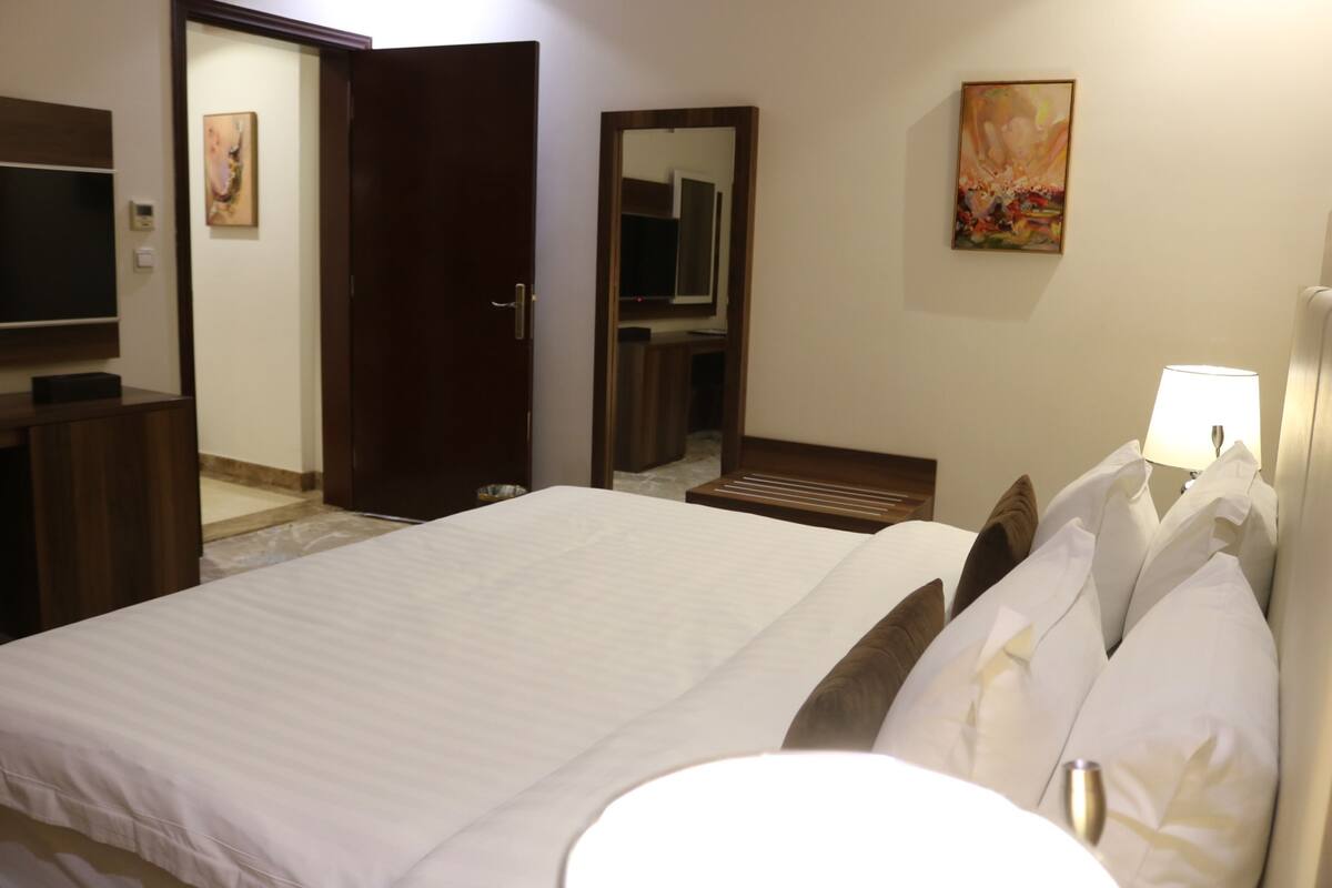 Une chambre d’hôtel avec un grand lit, une télévision, un miroir et un tableau au mur.