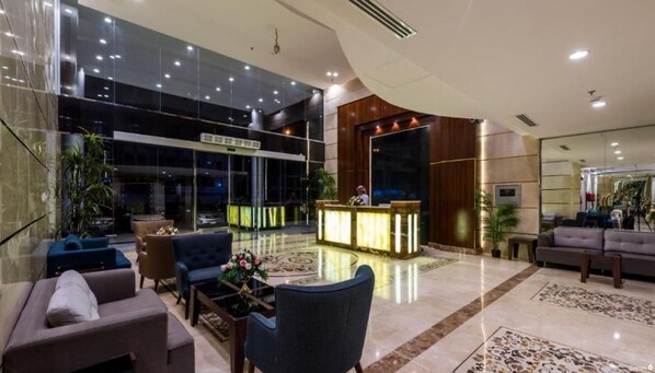 Un moderno vestíbulo de hotel con mostrador de recepción, zona de estar y ventanas amplias.