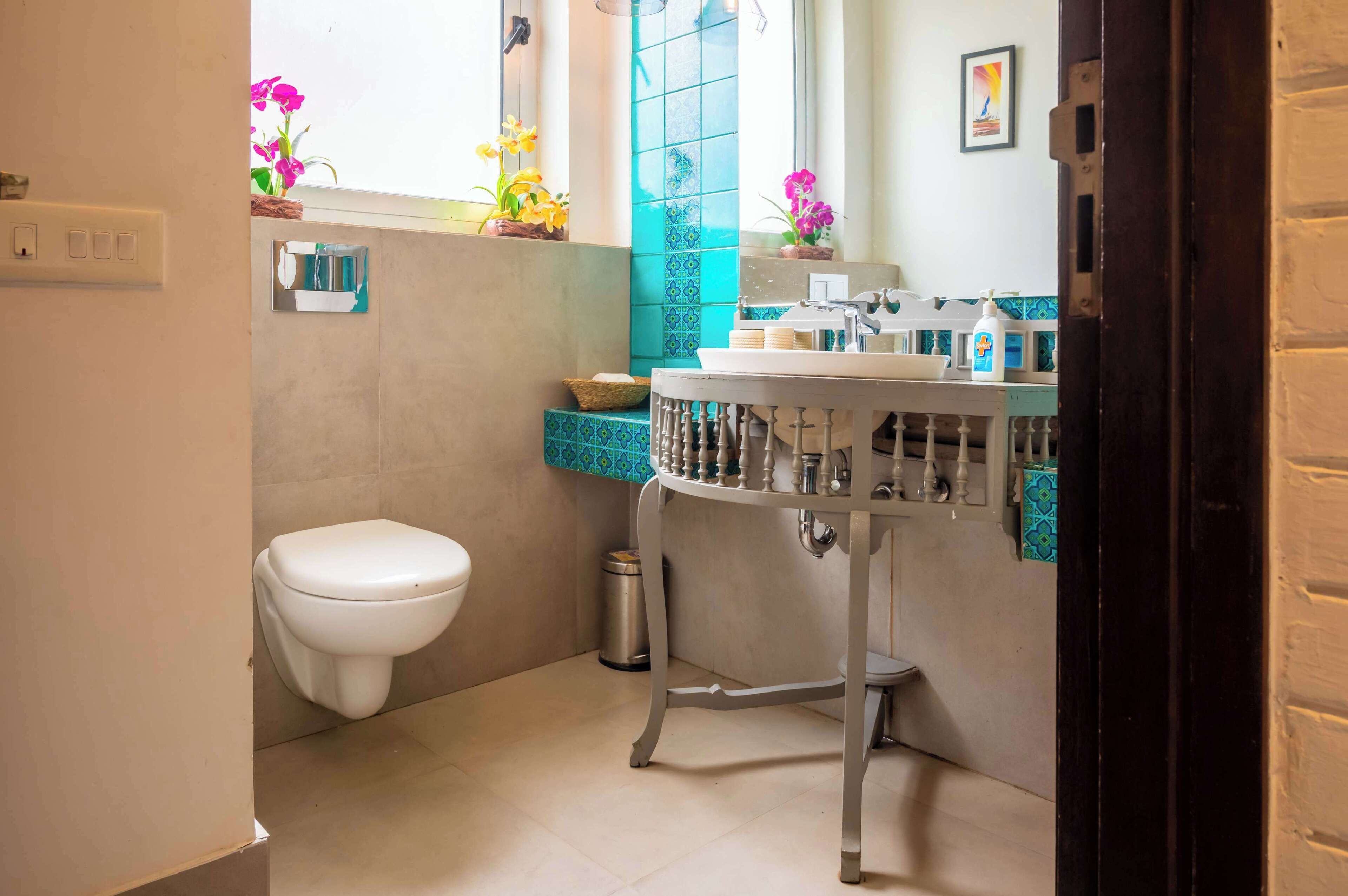 Un baño con inodoro, lavamanos y ventana con flores.