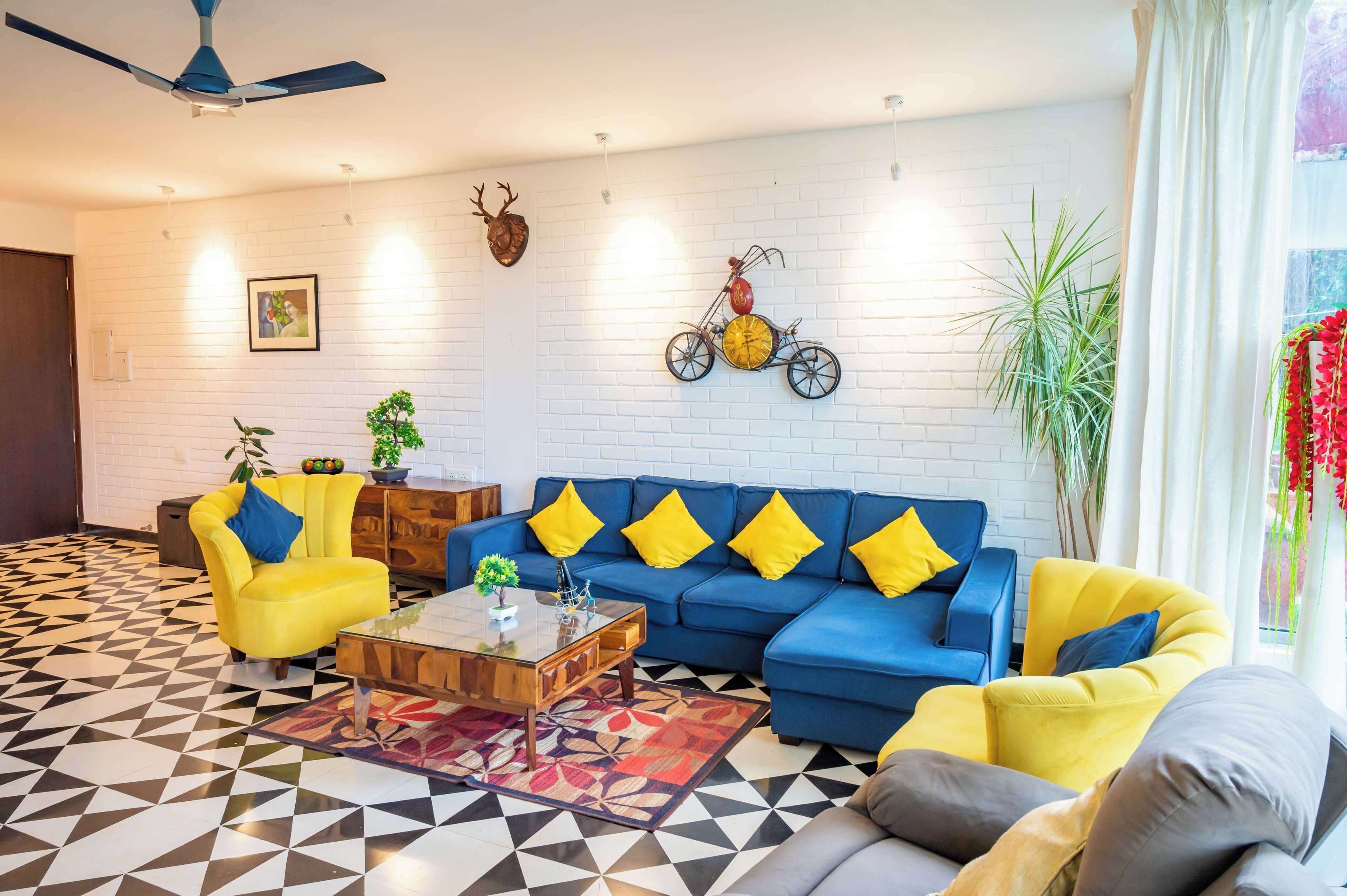 A living room with a blue sofa, yellow armchairs, a wooden coffee table, and a patterned rug.