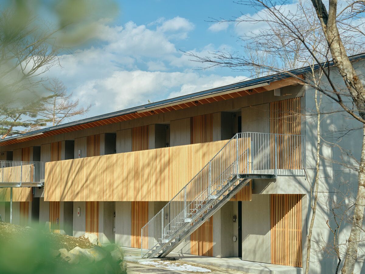 A modern building with a central staircase, multiple balconies, and a flat roof.