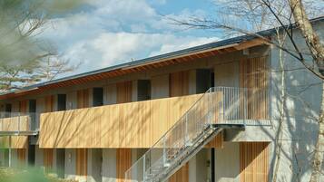 A modern building with a central staircase, multiple balconies, and a flat roof.
