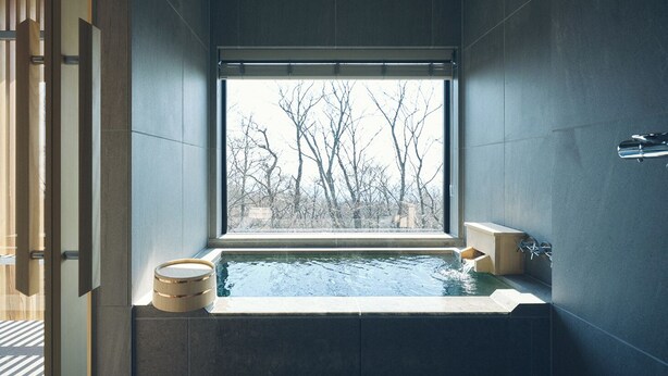 Une salle de bain moderne avec une grande fenêtre, une baignoire et un tabouret en bois.