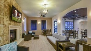 A spacious living area with a fireplace, comfortable seating, a television, and a dining area with tables and chairs.