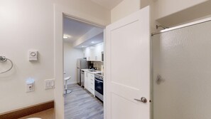 A modern kitchen with white cabinets, a built-in oven, and a stainless steel refrigerator. - Snow Creek #39 Suite | 3 Peaks Rentals (Sun Peaks)