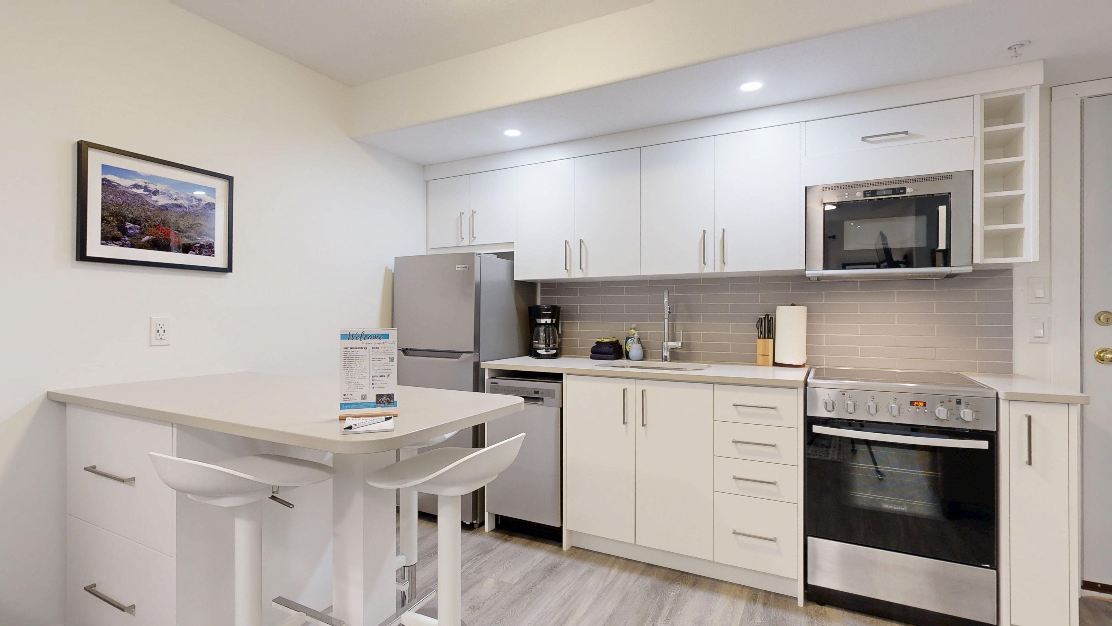 A compact kitchen with white cabinetry, a built-in microwave, a stove, and a coffee maker.