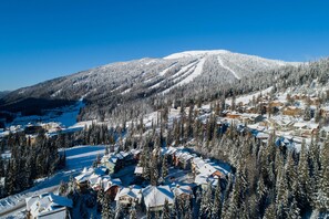 Ein schneebedeckter Berg mit einem Skigebiet und Berghütten.