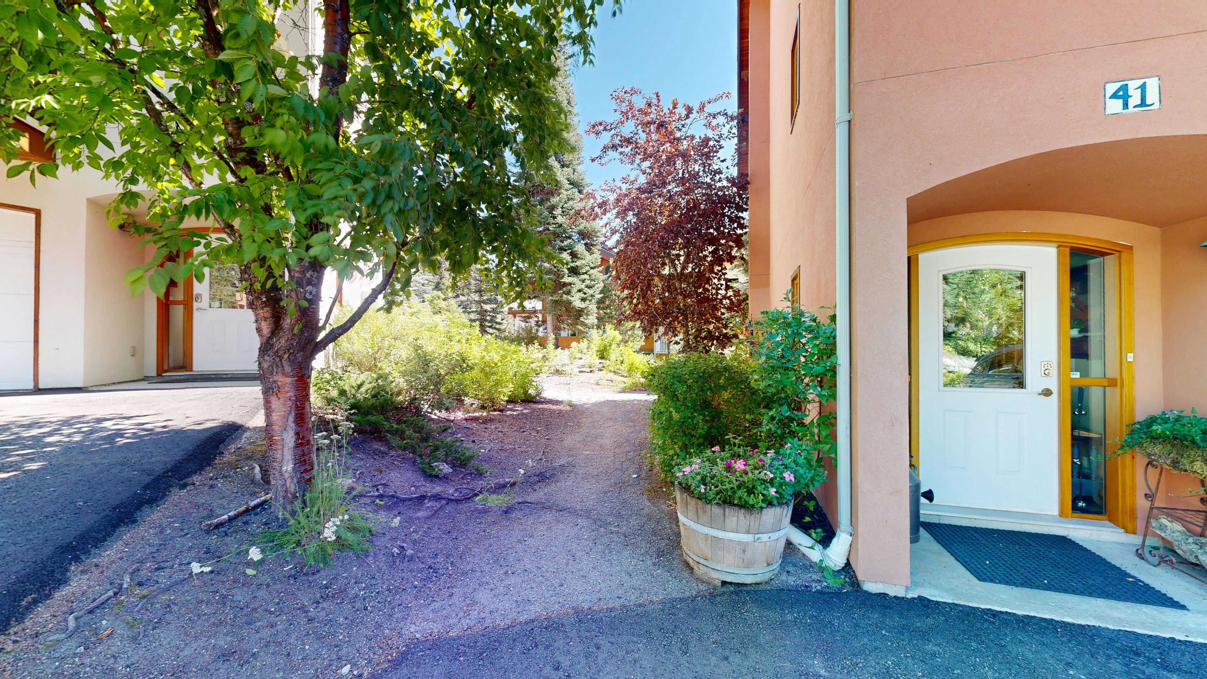 A building entrance with a gravel path, a wooden door, and a number sign.