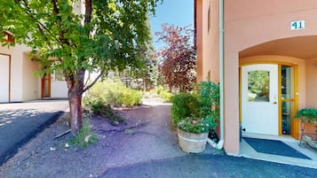 A building entrance with a gravel path, a wooden door, and a number sign.
