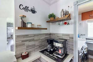 A modern kitchen with a coffee station, a coffee machine, and a wall-mounted shelf with kitchen utensils.