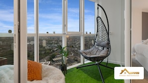 A modern bedroom with a large window, a hanging chair, and a view of the city. - 2BR 2Bath Central London Luxury Flat Skyview (London)