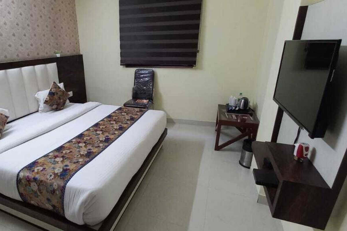 Une chambre d’hôtel avec un lit, une télévision, un bureau et une chaise.