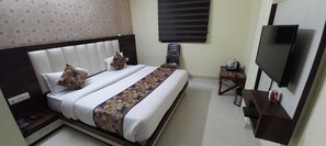 A hotel room with a bed, a TV, a desk, and a chair. - Satyadeep Inn (Gorakhpur)
