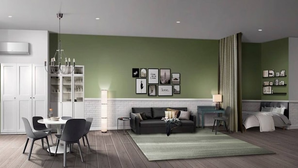 Ein modernes Wohnzimmer mit einer grünen Akzentwand, einem weißen Kamin, einem Essbereich mit rundem Tisch und Stühlen sowie einem Sofa mit Couchtisch.
