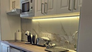 Eine moderne Küche mit weißen Schränken, einer eingebauten Mikrowelle, einem Toaster und einem Geschirrspüler.