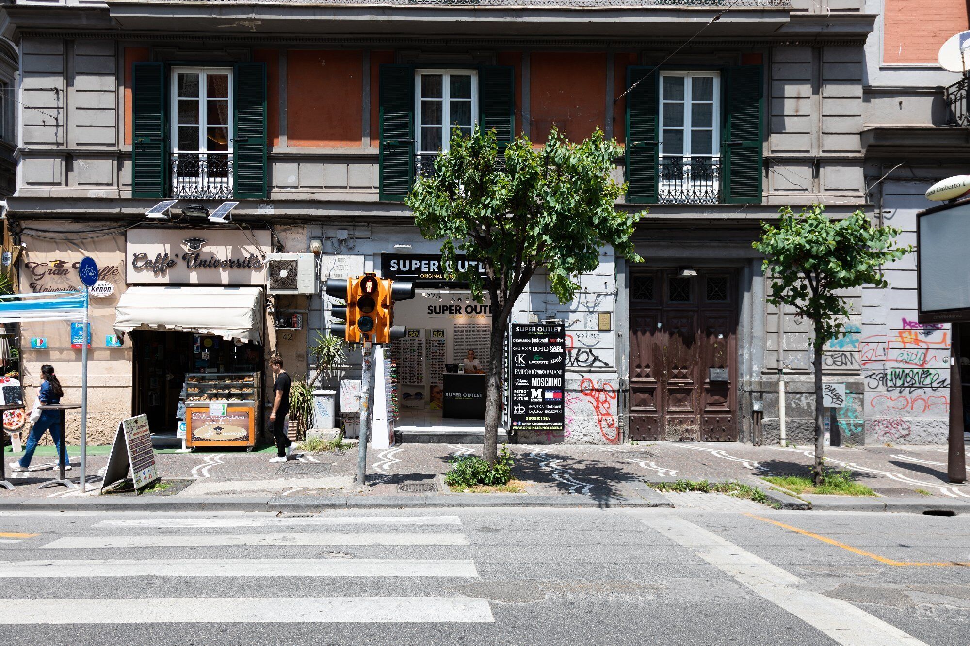 A street view with a café named "Caffe Universita" and a "Super Outlet" store.